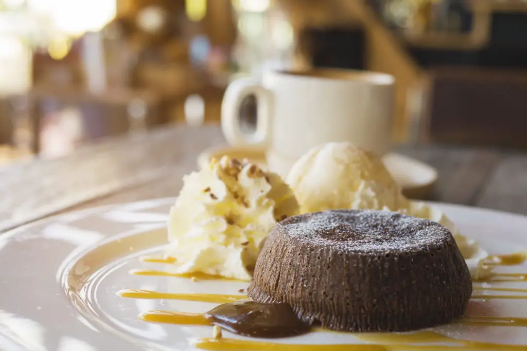 Chocolate lava cake in white plate with coffee cup in coffee shop