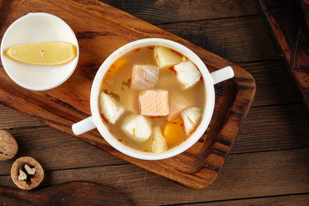 Ukha fish soup with lemon on the wooden table