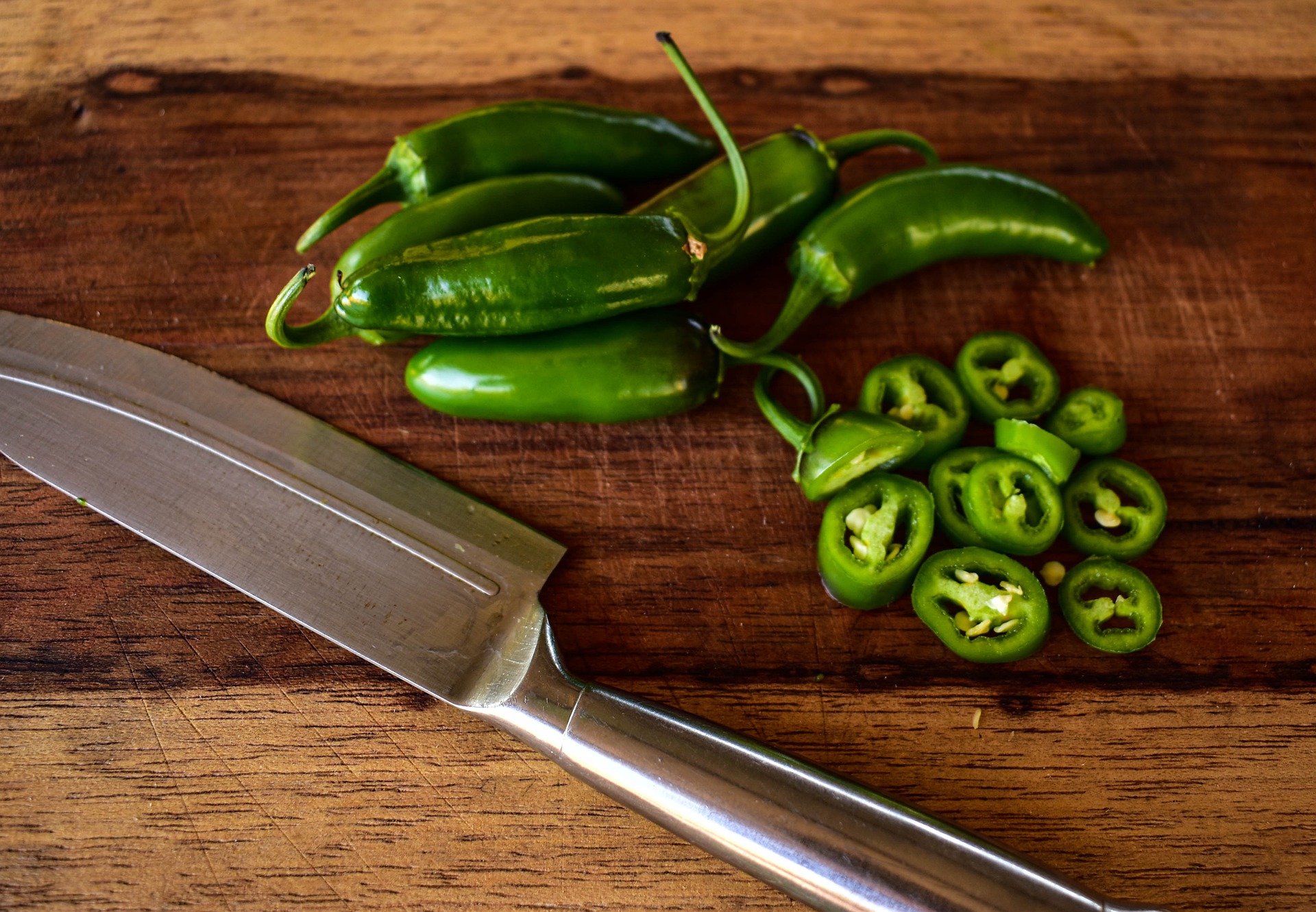 Jalapenos with a knife on a wooden background