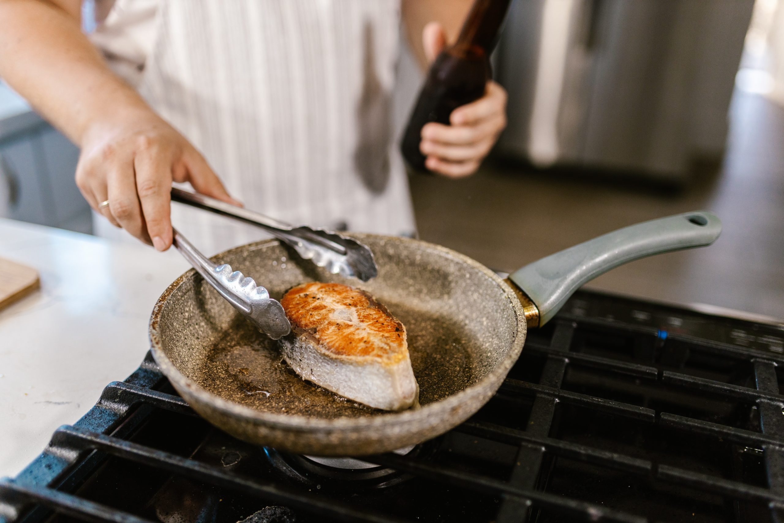 man cooking fish slice in a pan